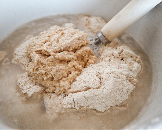 Bowl with a sourdough dough mixture and a wooden spoon
