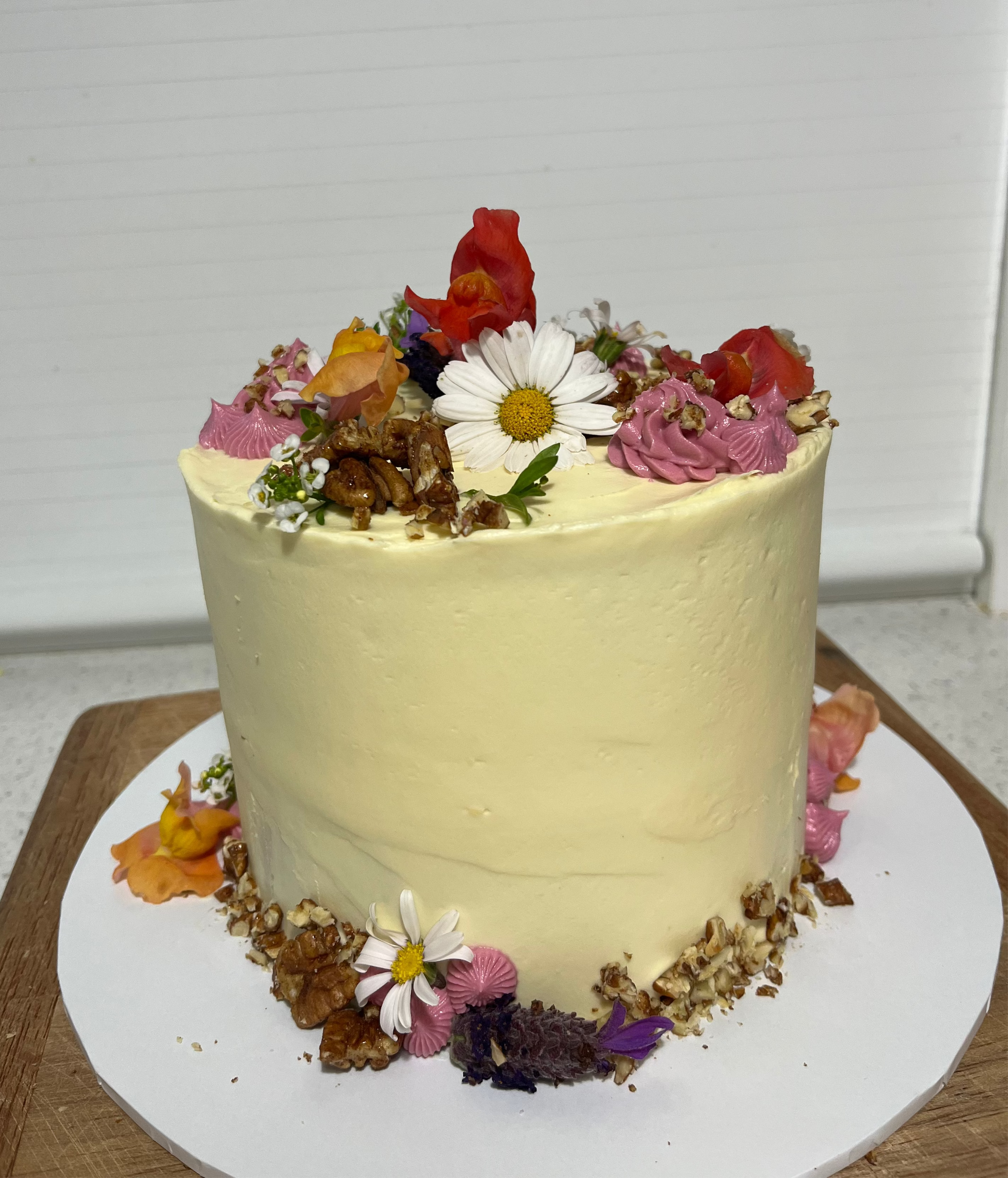 Decorative sourdough carrot cake cake with flowers on a white plate against a white background